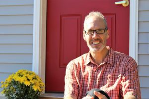 man smiling at camera in front of red door