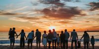 family members holding hands on a beach at sunset in shadow